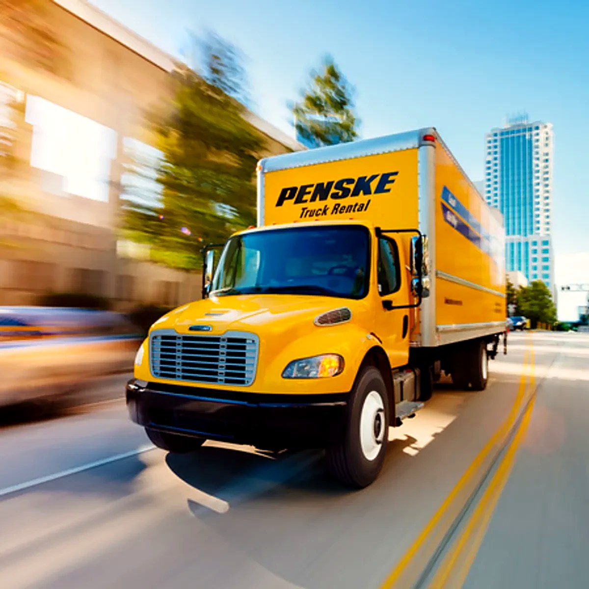 Yellow Penske Truck Rental box truck rolling through the city